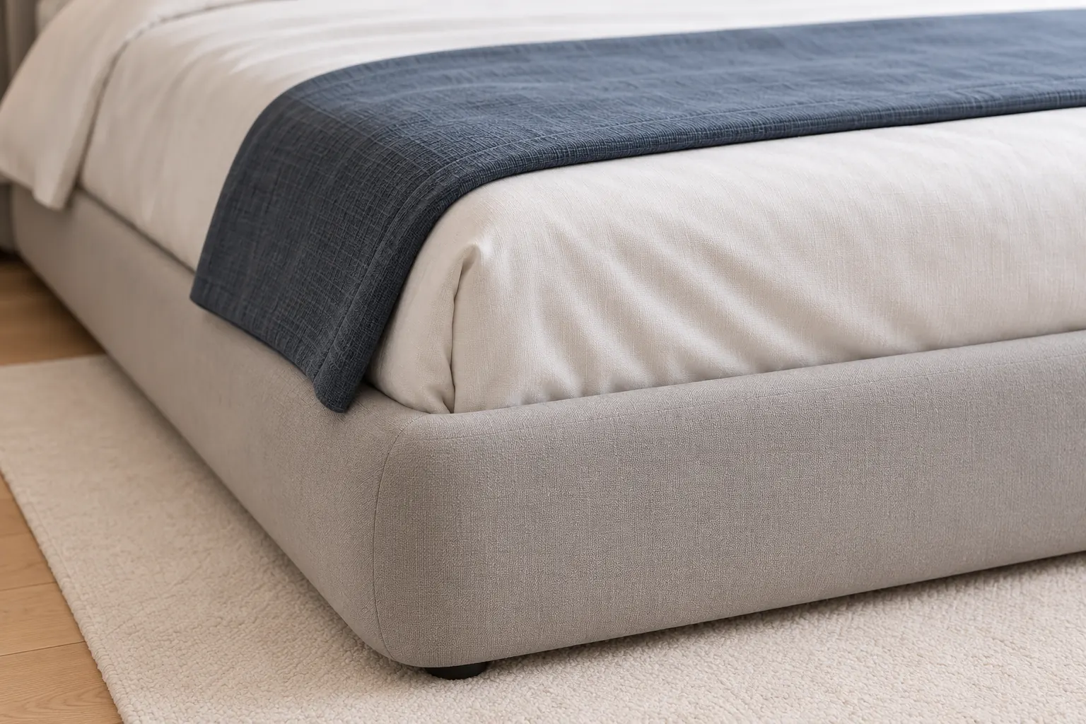 Close detail of ivory upholstery and a slate-blue bed throw